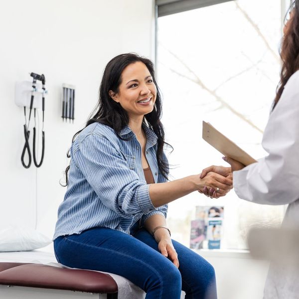 Mid adult female patient shakes hands with her doctor during annual checkup