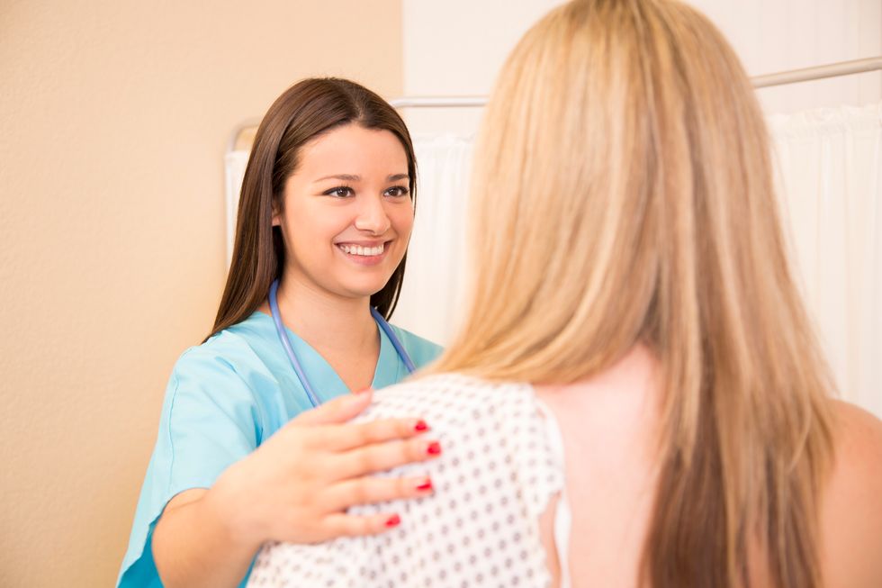 Mid-adult woman receives annual breast exam from her Latin descent gynecologist