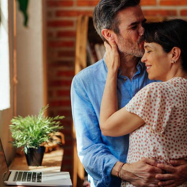 middle-aged man kissing his wife on the forehead while she enjoying in his hug