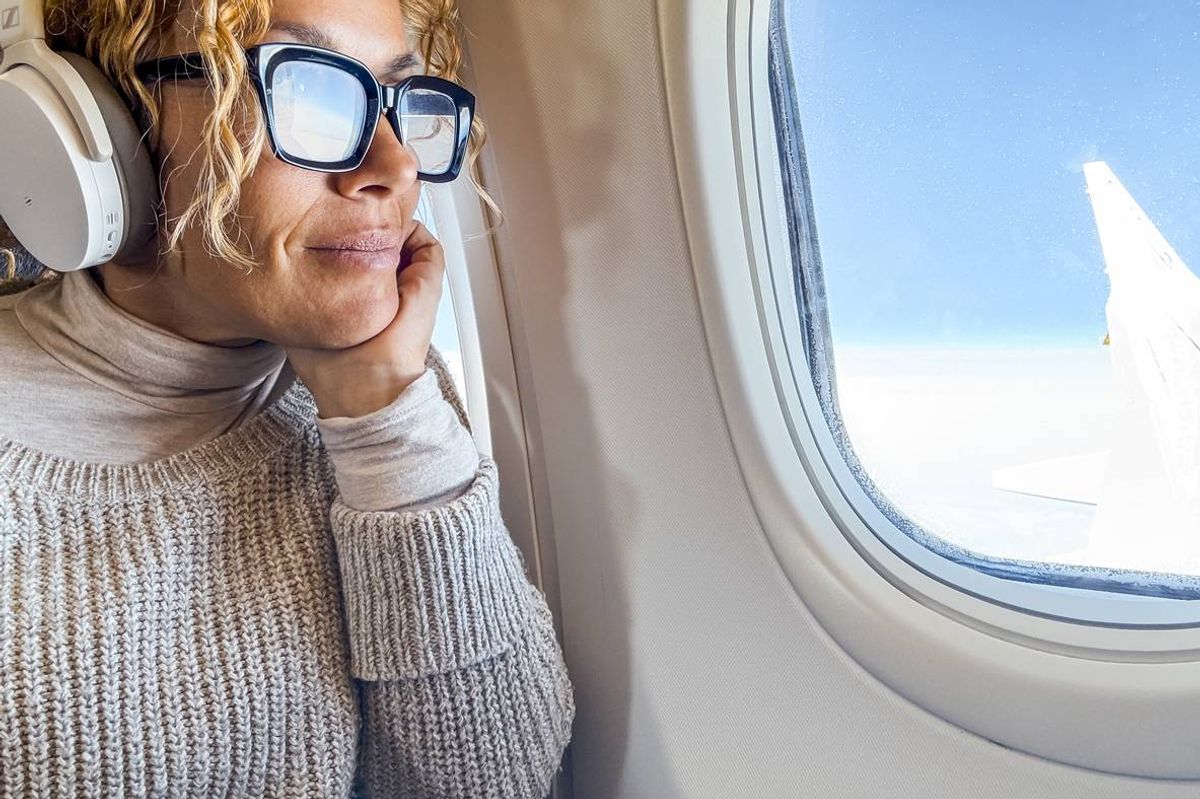 middle-aged woman listens to music and relaxes while sitting in a airplane seat