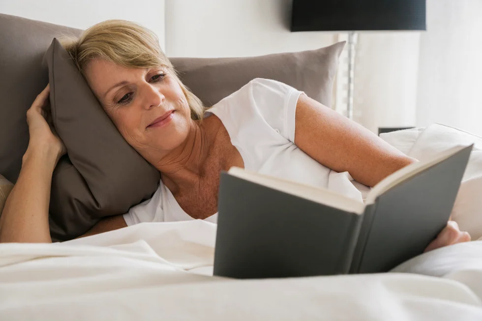Middle-aged woman reading in bed