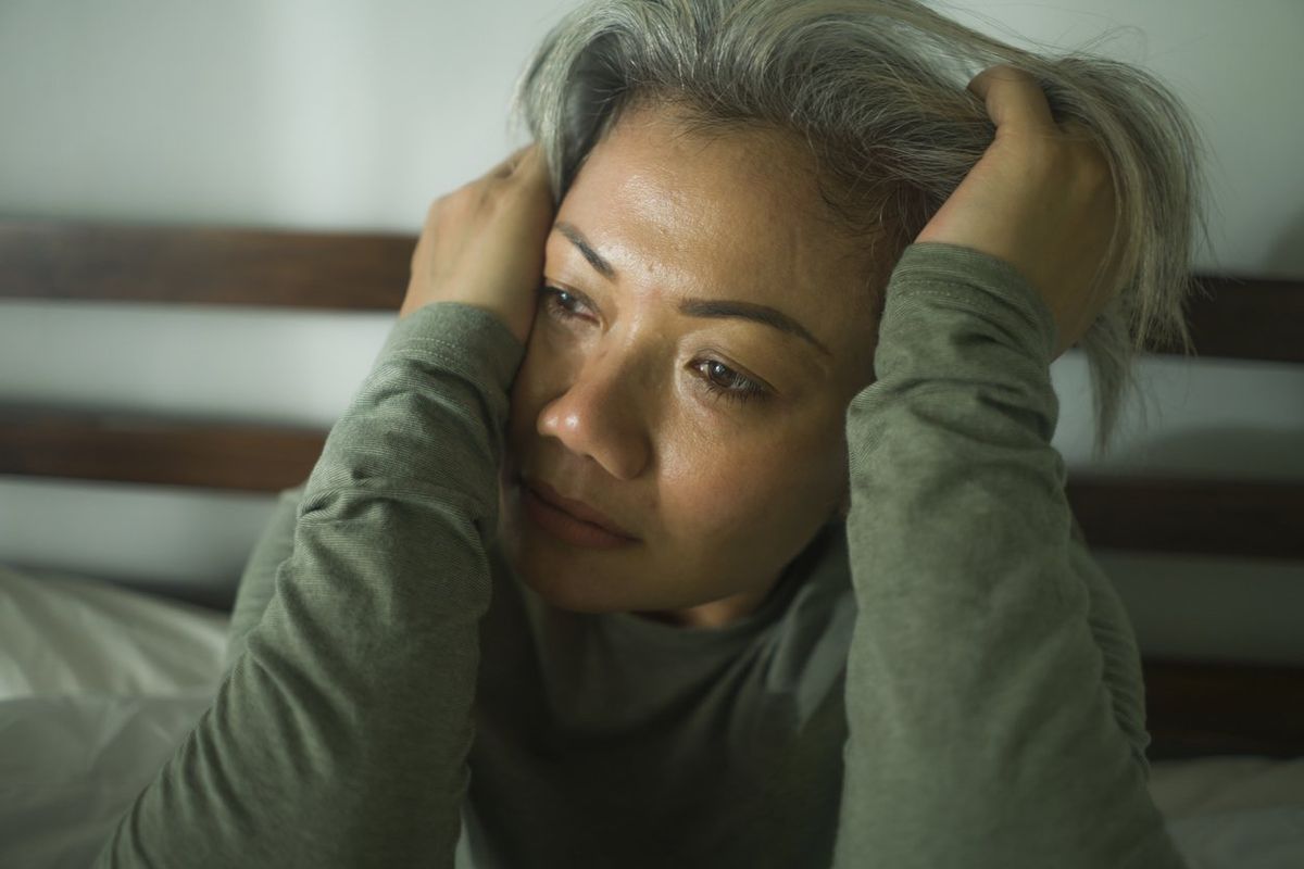middle aged woman with grey hair sad and depressed in bed feeling frustrated
