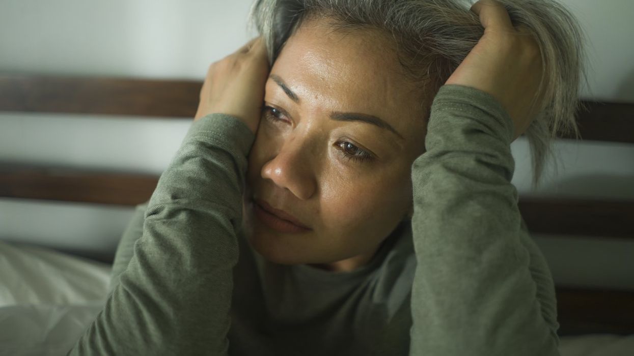 middle aged woman with grey hair sad and depressed in bed feeling frustrated