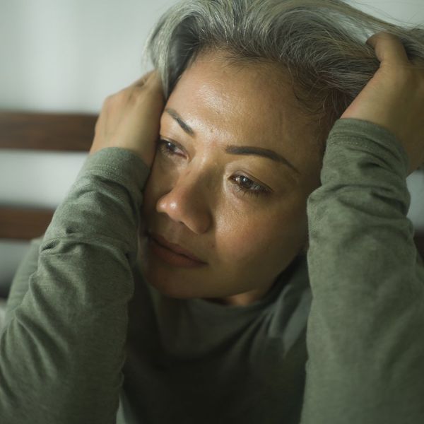 middle aged woman with grey hair sad and depressed in bed feeling frustrated