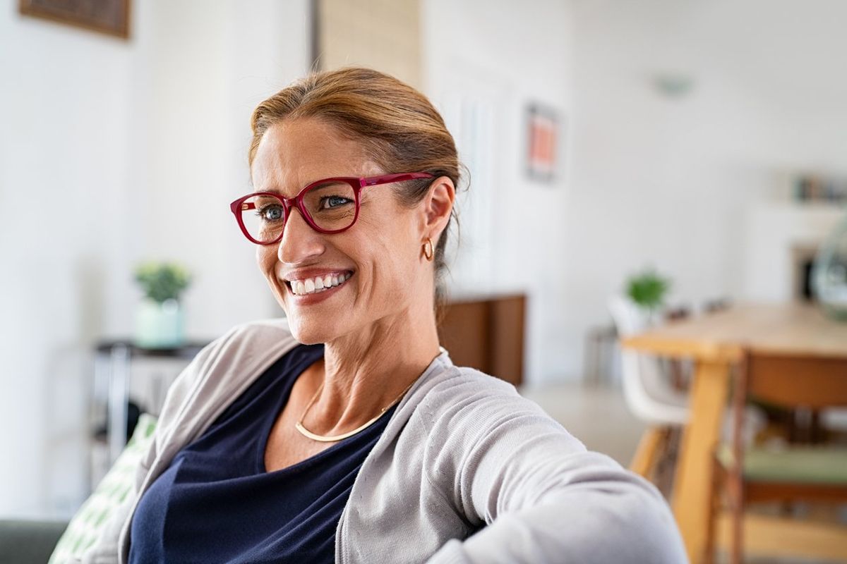 Middle aged woman with spectacles relaxing on couch at home in living room