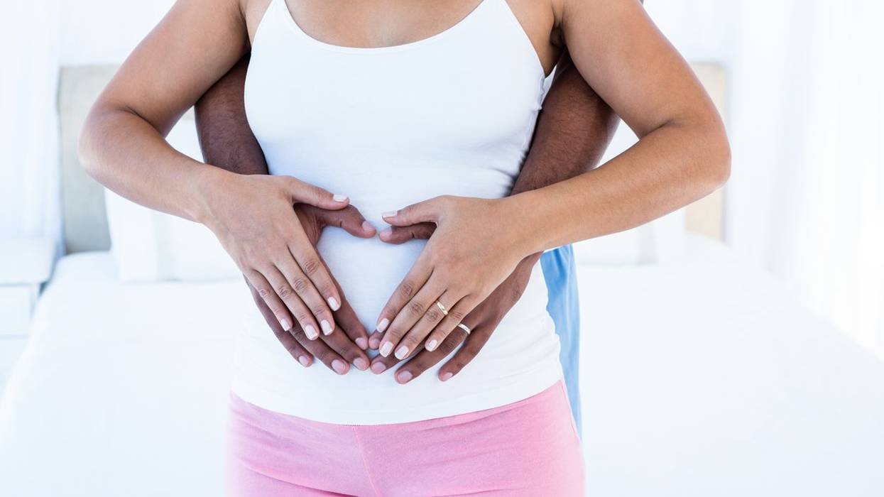 Midsection of couple hands making heart shape on belly