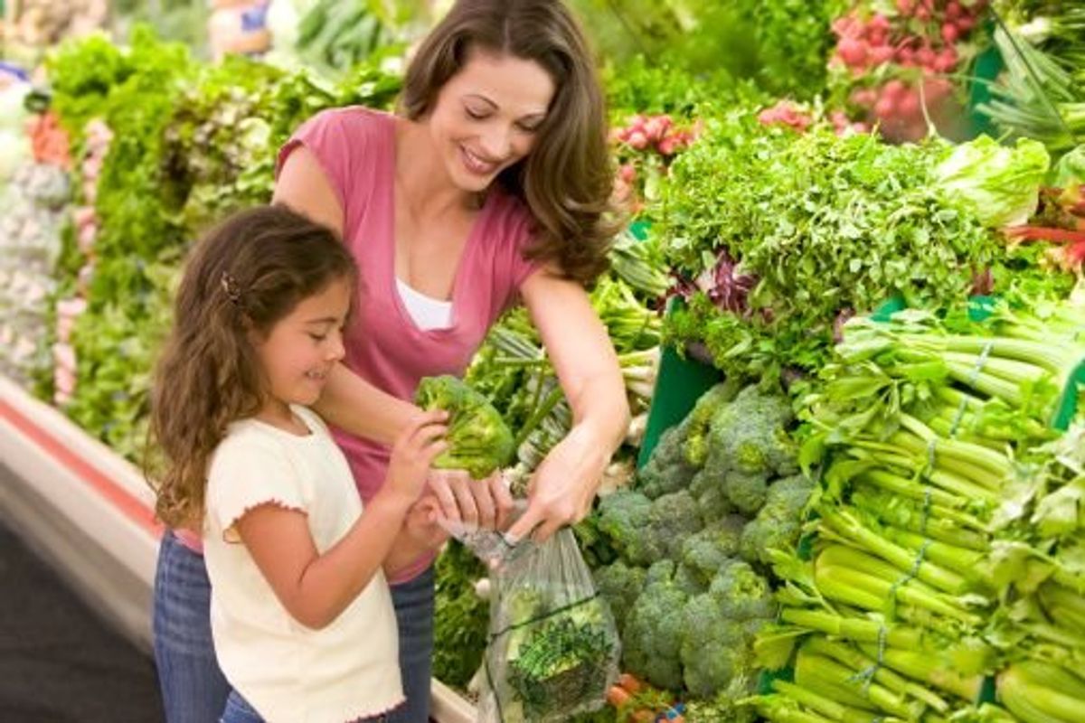 mom and child picking out broccoli in the produce section of a supermarket