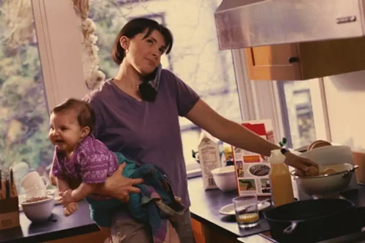 mom holding a baby while making dinner
