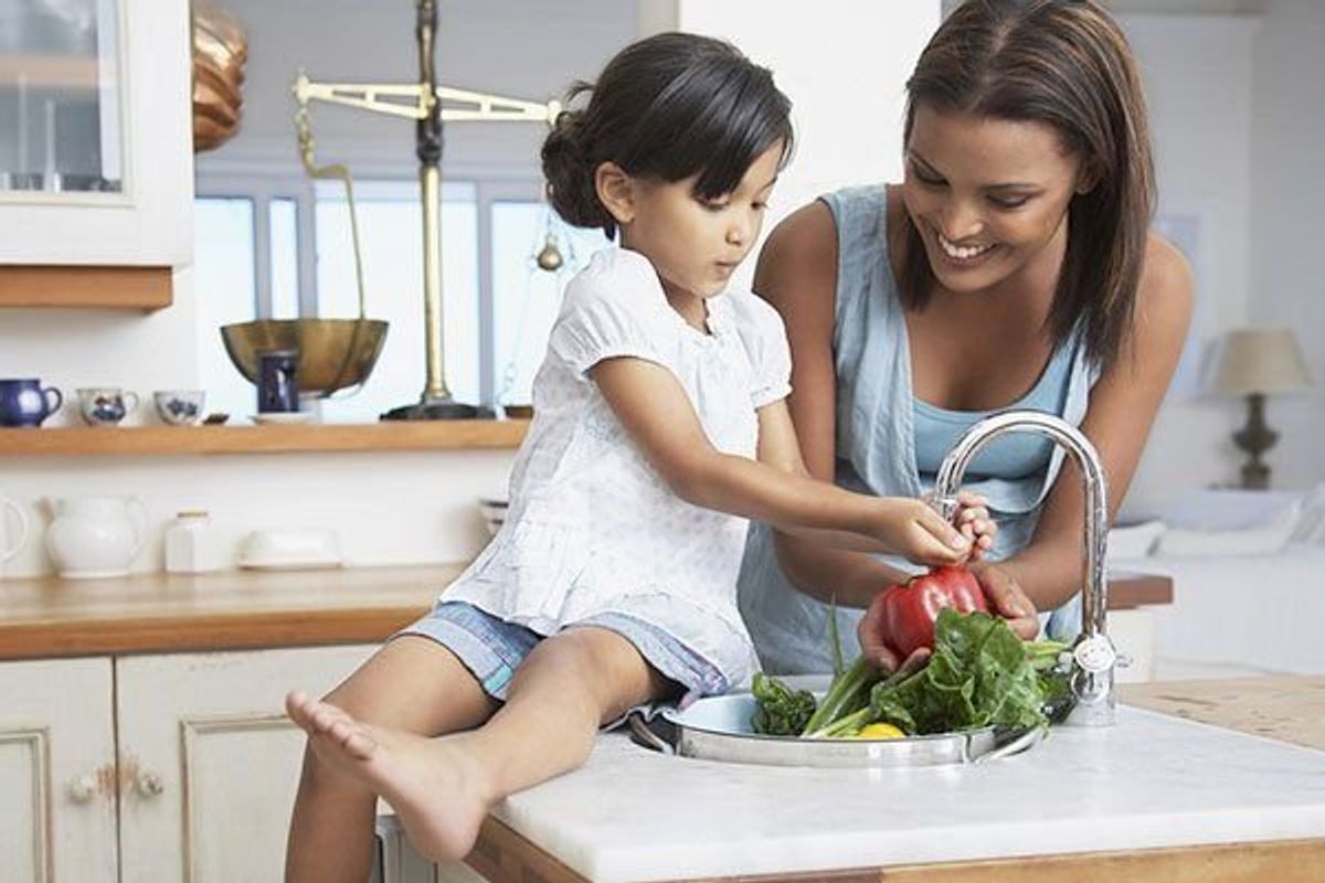 mother and daughter in the kitchen washing vegetables