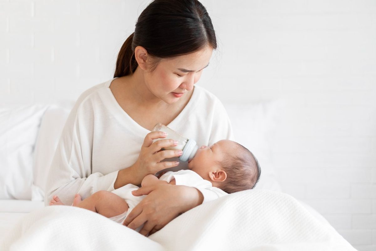 Mother feeding formula to Asian newborn