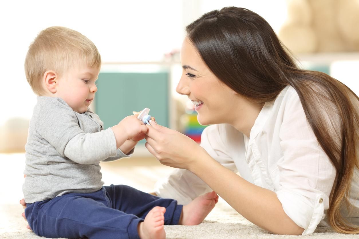 mother giving a pacifier to her baby