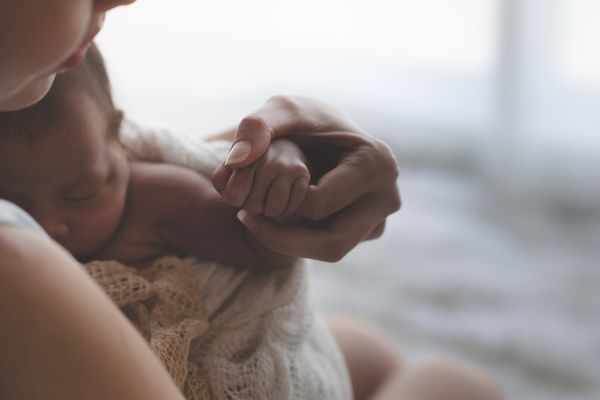 Mother holding hands Asian female newborn baby and sunlight in the morning
