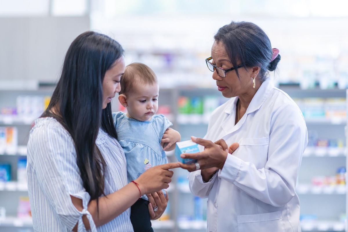 Mother with baby girl picks up medication at the pharmacy