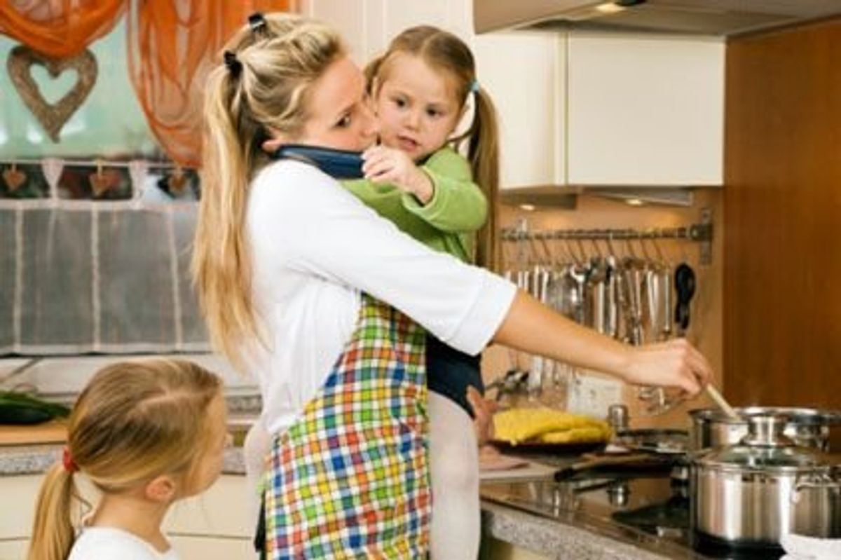 mother with two daughters talking on the phone while making dinner