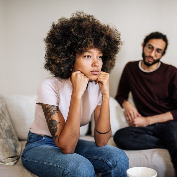 Multi ethnic couple in living room drinking coffee or tea and expressing negative emotions