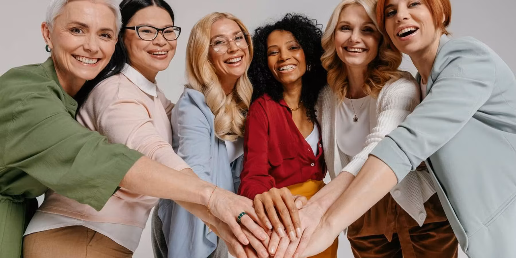 Multi-ethnic group of happy mature women holding hands