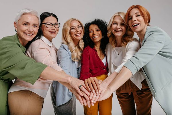 Multi-ethnic group of happy mature women holding hands