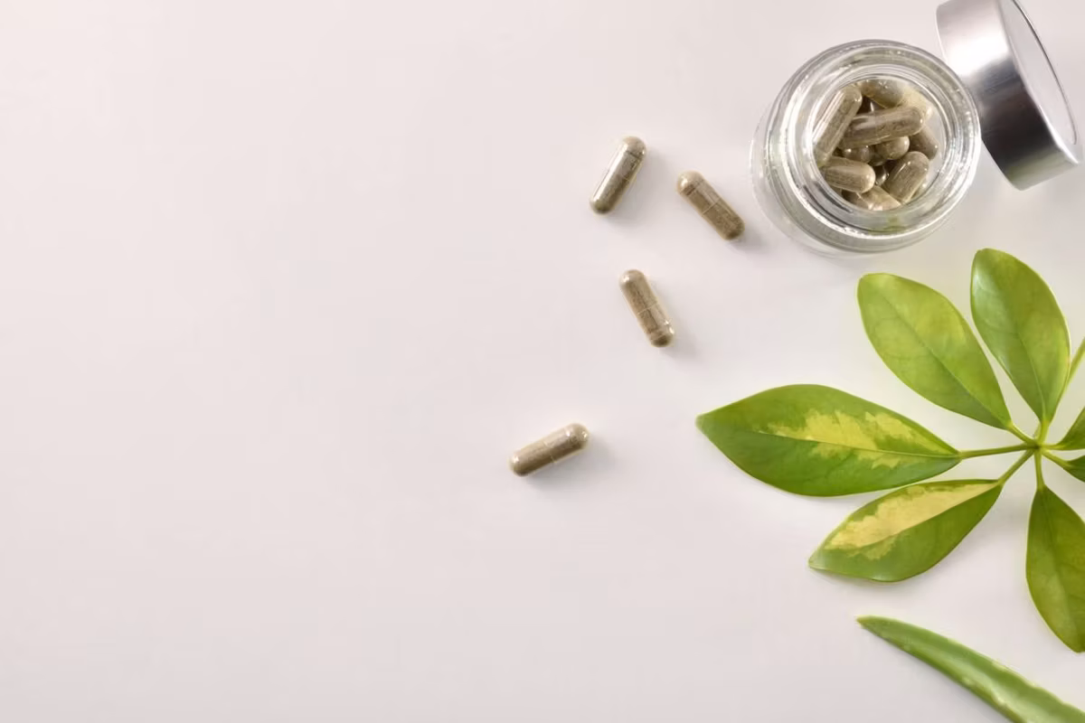 Natural medicine capsules in open glass jar on table