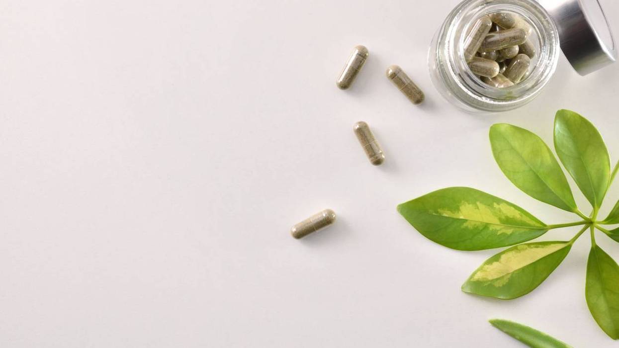 Natural medicine capsules in open glass jar on table