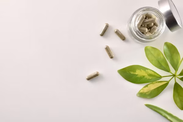 Natural medicine capsules in open glass jar on table