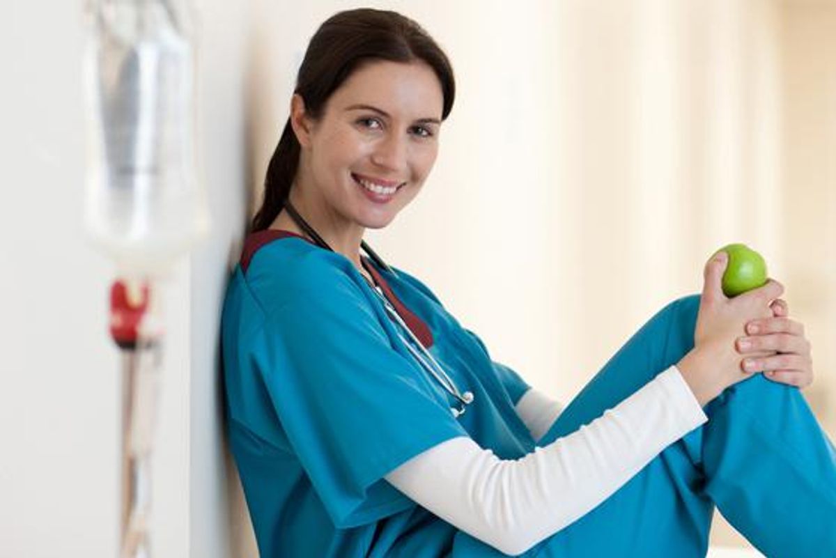 Nurse sitting with apple in hospital corridor