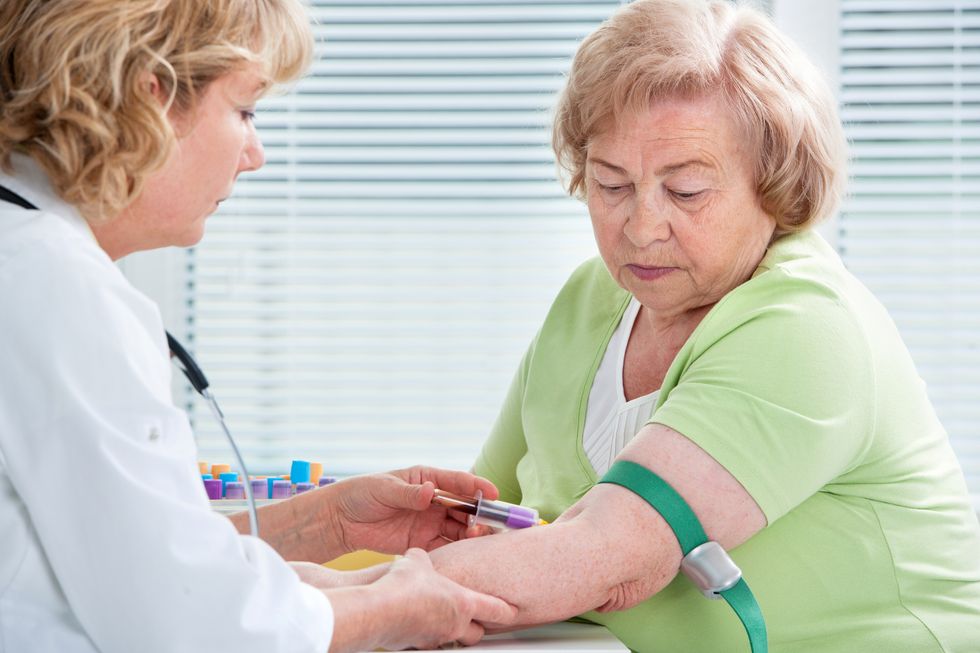 Nurse taking blood sample from patient at the doctors office to check cholesterol levels