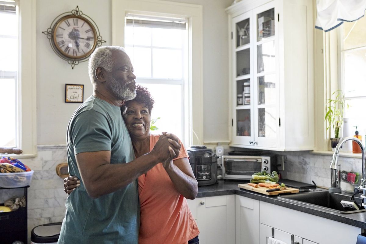 older couple hugging and dancing in the kitchen