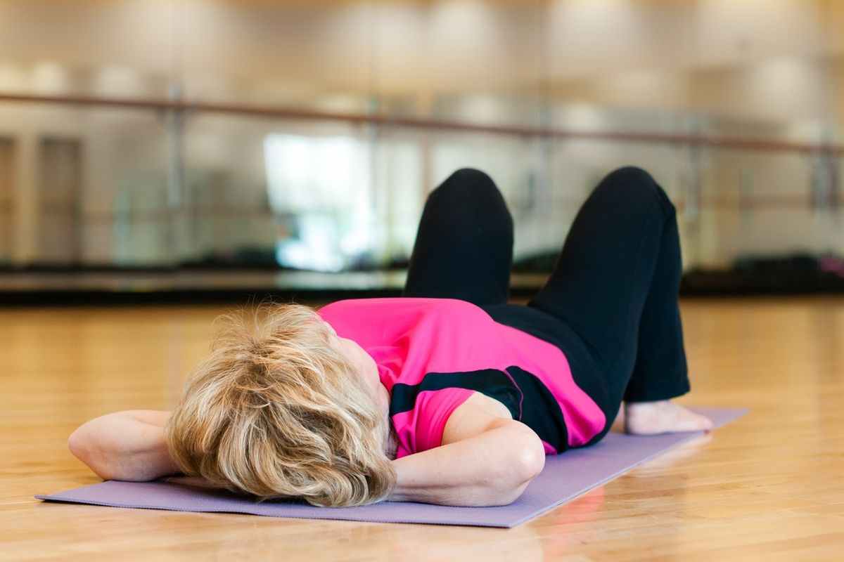 older woman doing exercises on a yoga mat