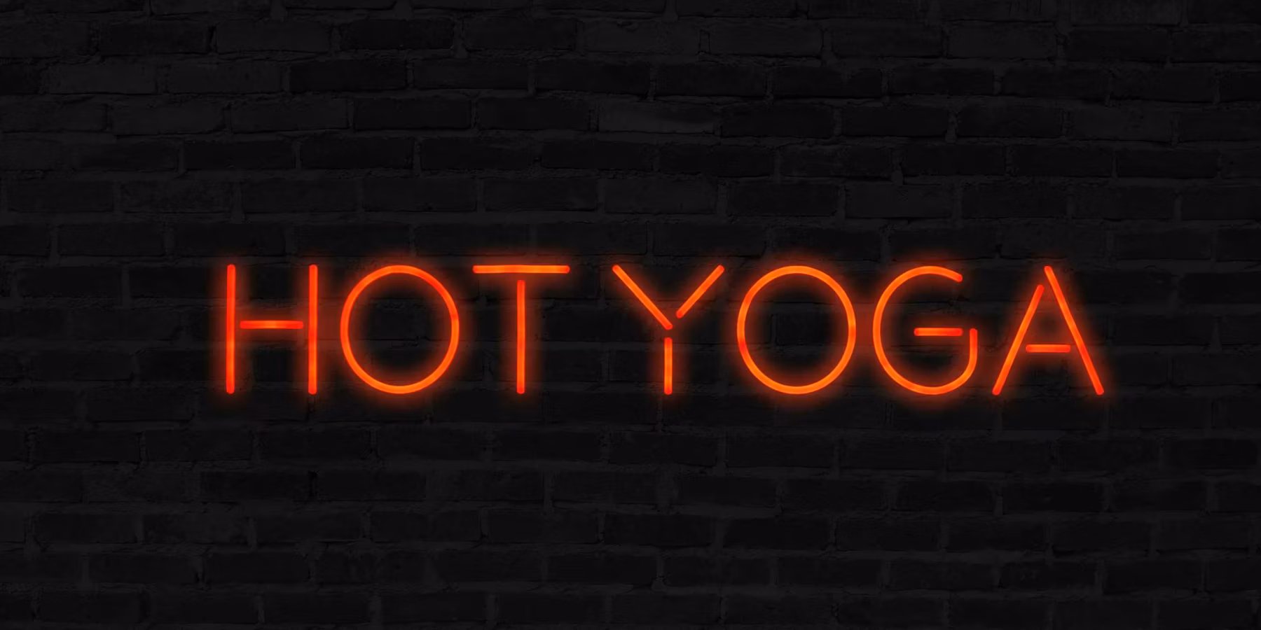 Orange Hot Yoga neon sign with brick wall