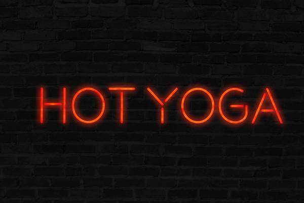 Orange Hot Yoga neon sign with brick wall