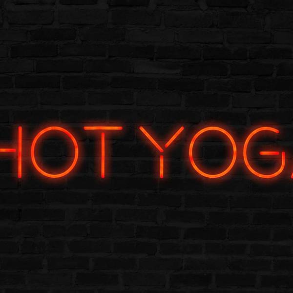 Orange Hot Yoga neon sign with brick wall