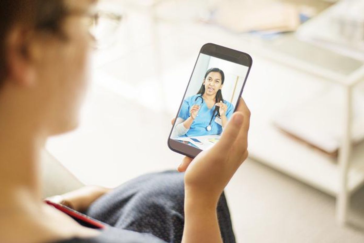 Over the shoulder shot of a patient talking to a doctor using of a mobile phone