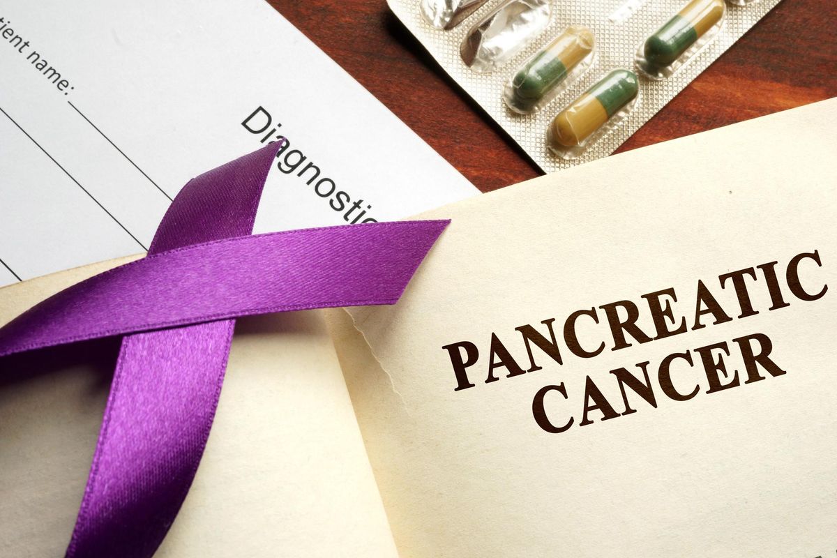 Pancreatic cancer written on a page and purple awareness ribbon