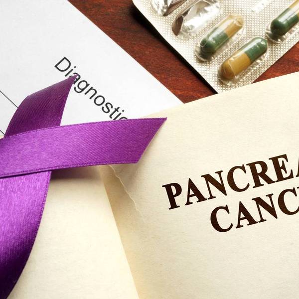 Pancreatic cancer written on a page and purple awareness ribbon