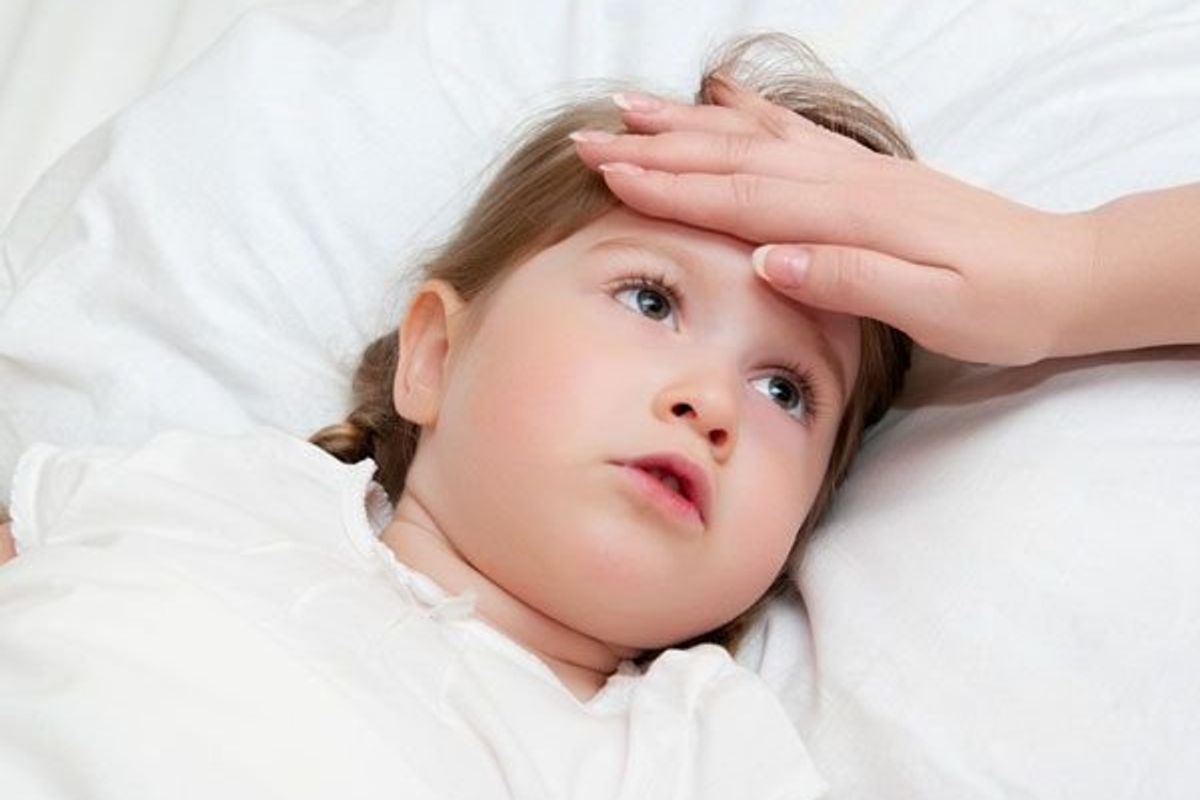 parents hand on the forehead of a sick child