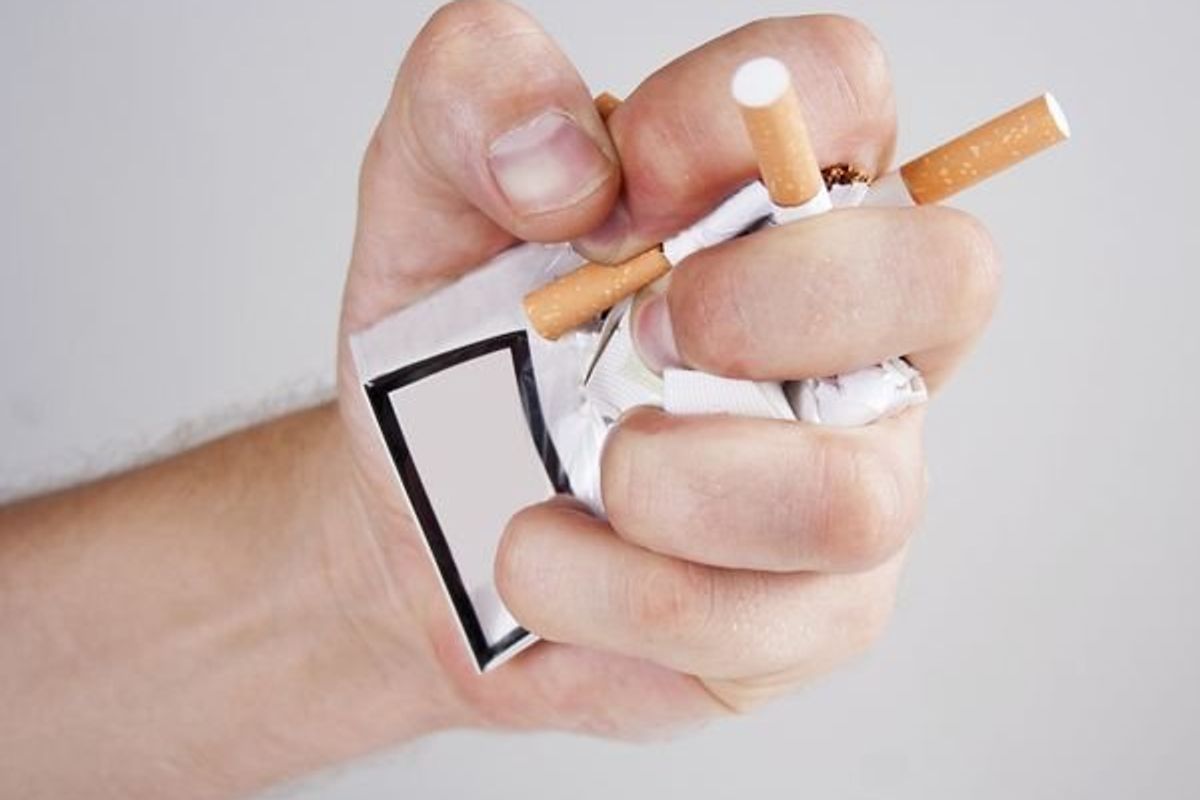 person crushing a pack of cigarettes