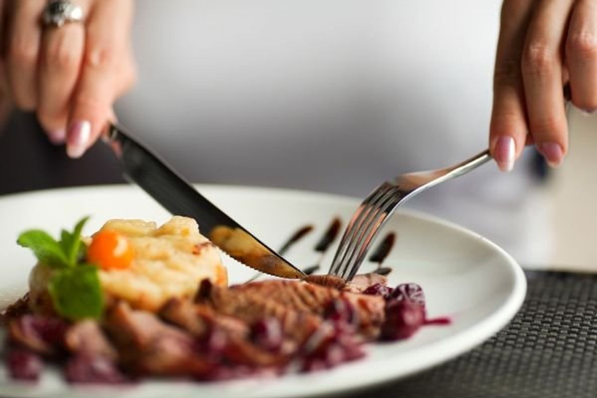 person cutting up food on a plate