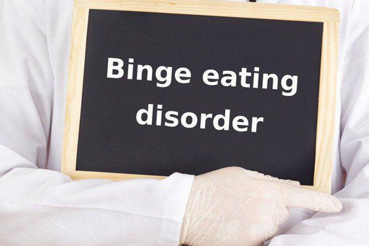 person holding a sign that says binge eating disorder