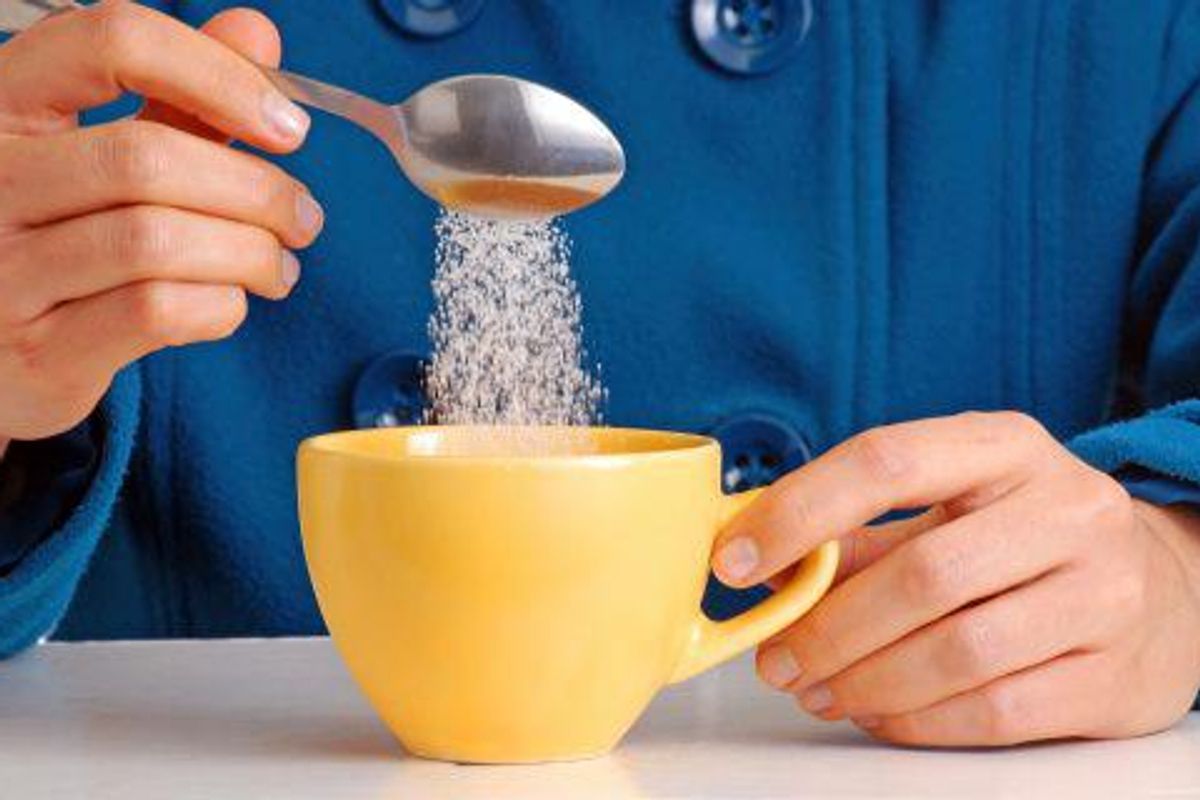 person putting sugar in their coffee