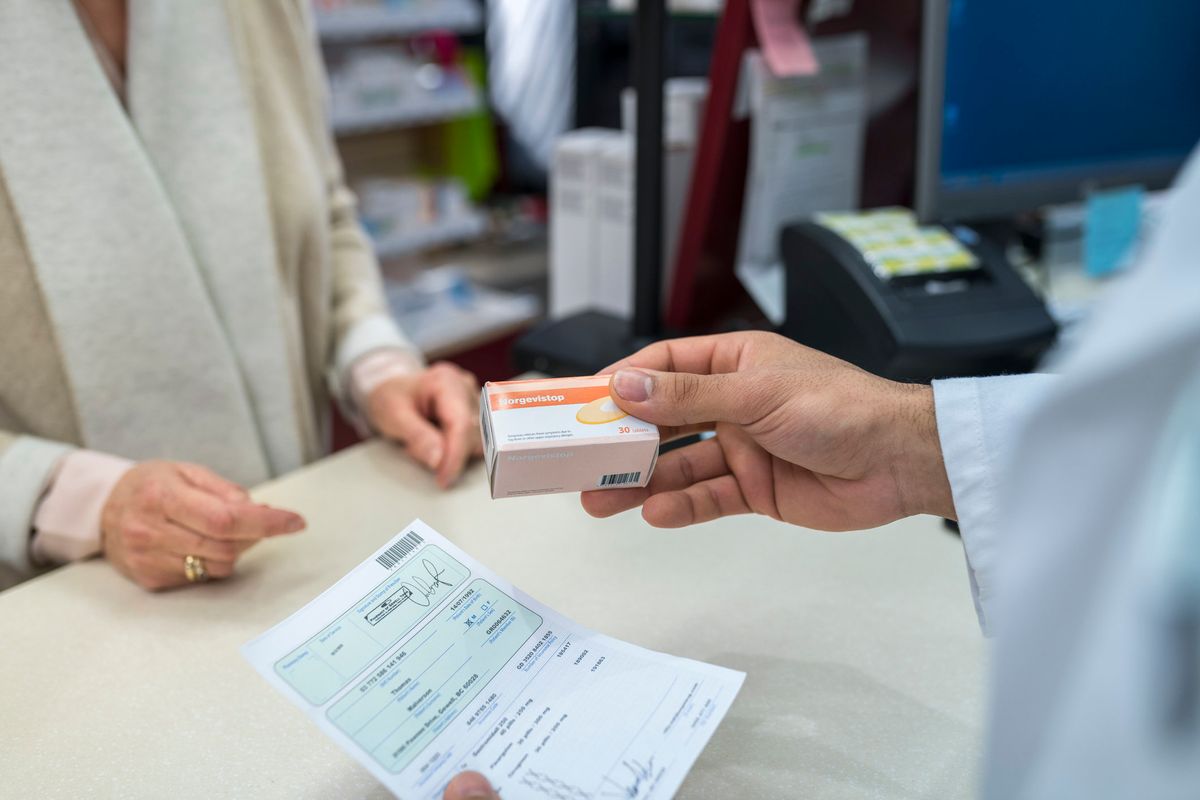 Pharmacist giving medicine box to customer