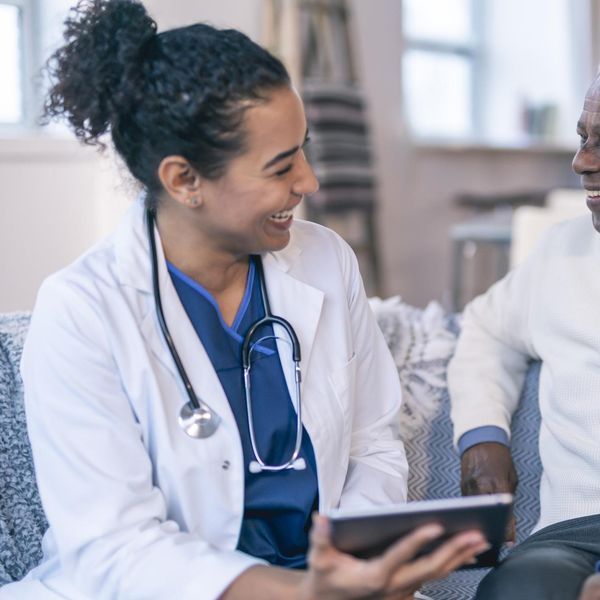 physician is meeting with a patient in the patient's home