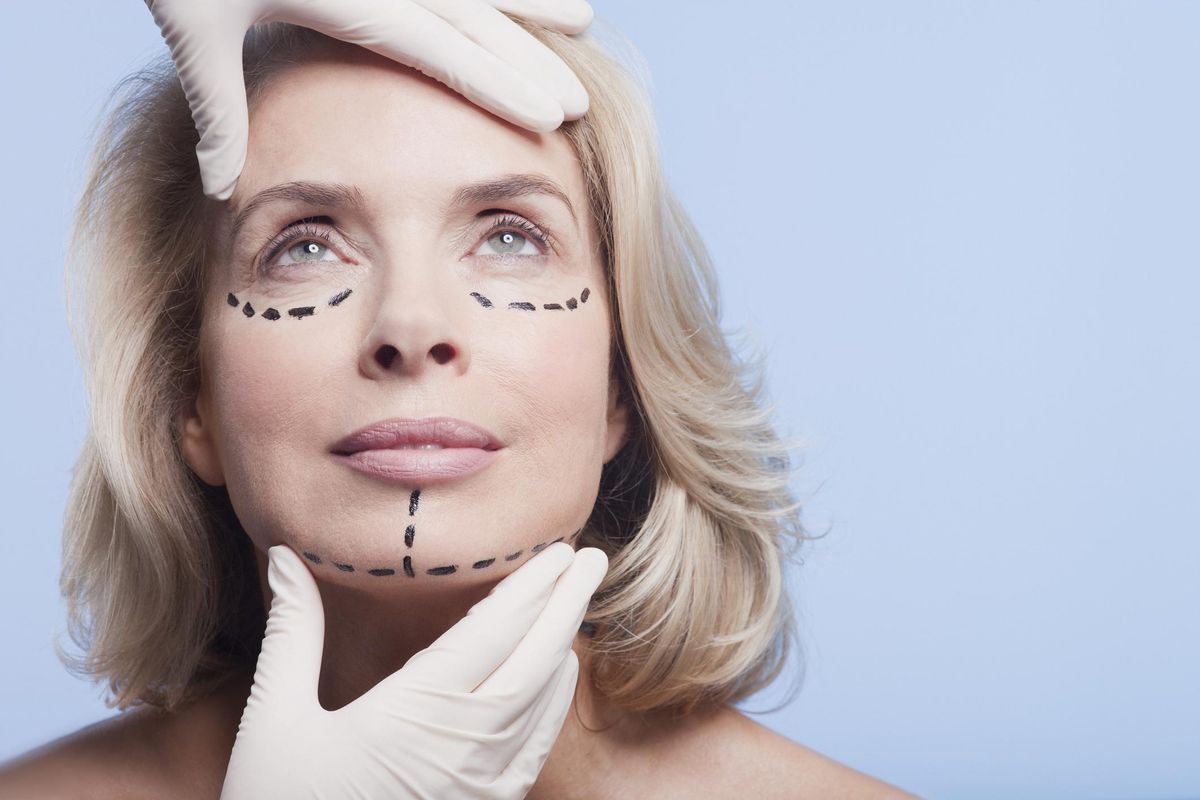 plastic surgeon holding woman's face with dotted lines