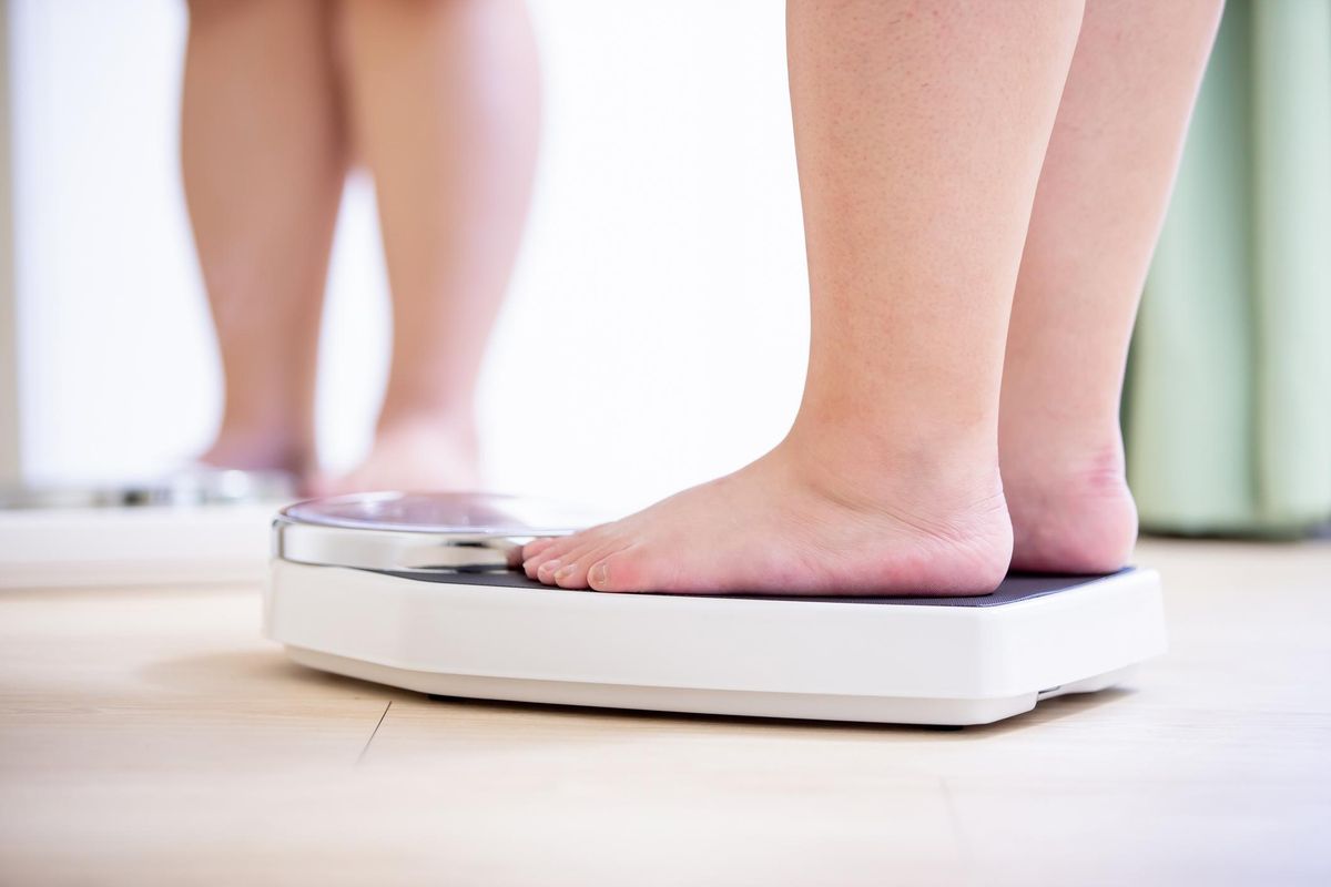 plus size asian girl look mirror and measure her weight by scale