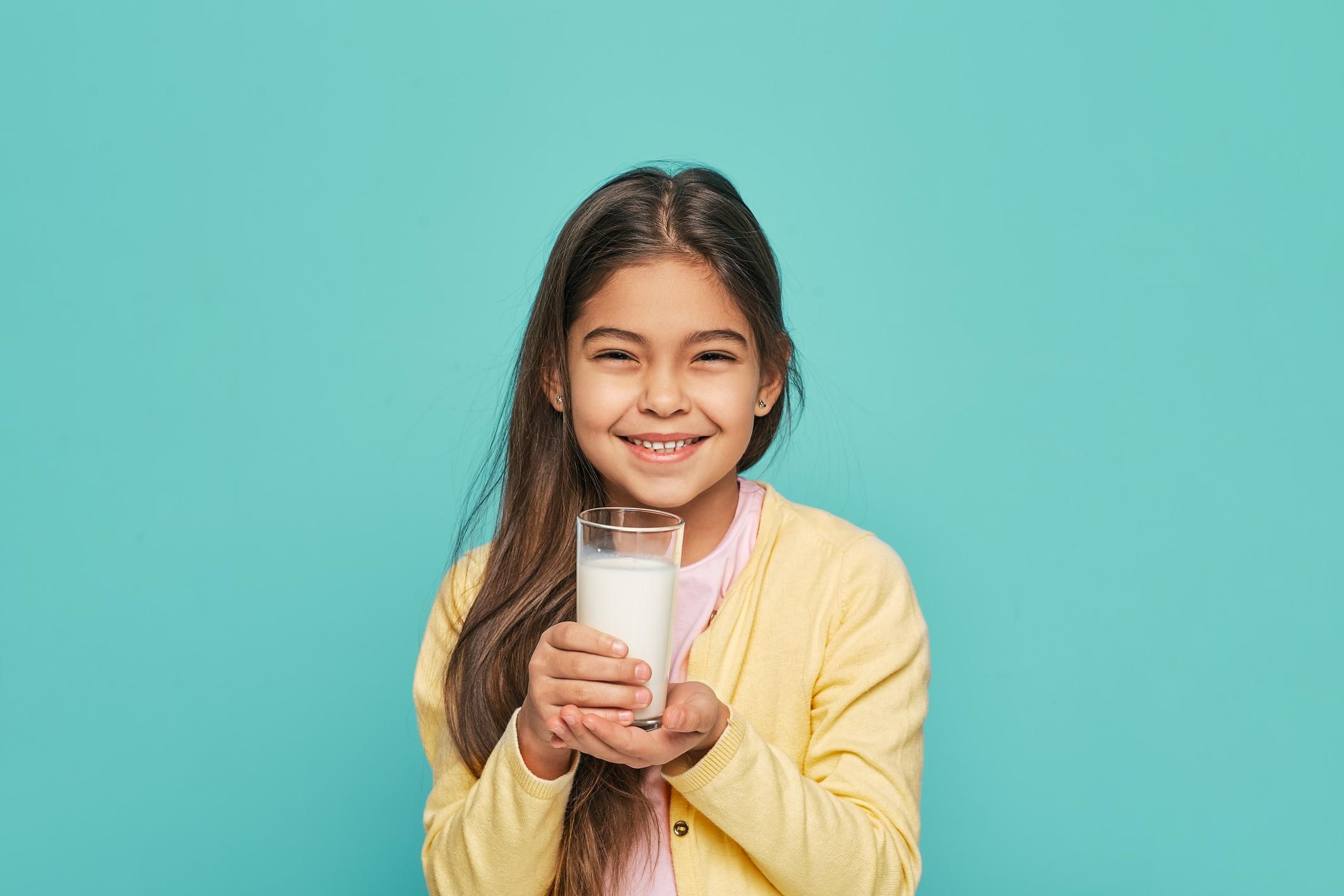 Portrait mixed race female kid with a glass of milk in her hands