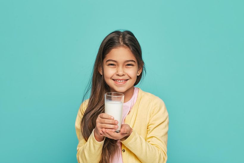 Портрет девочки смешанной расы со стаканом молока в руках