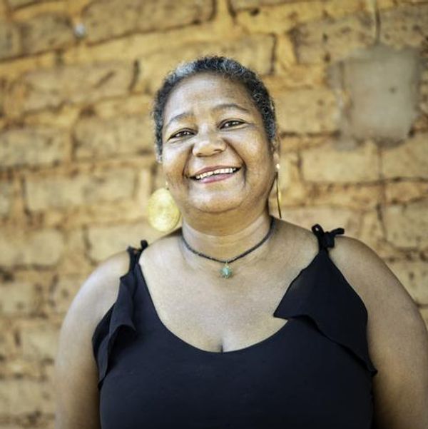 Portrait of a mature woman in front of a wattle and daub house