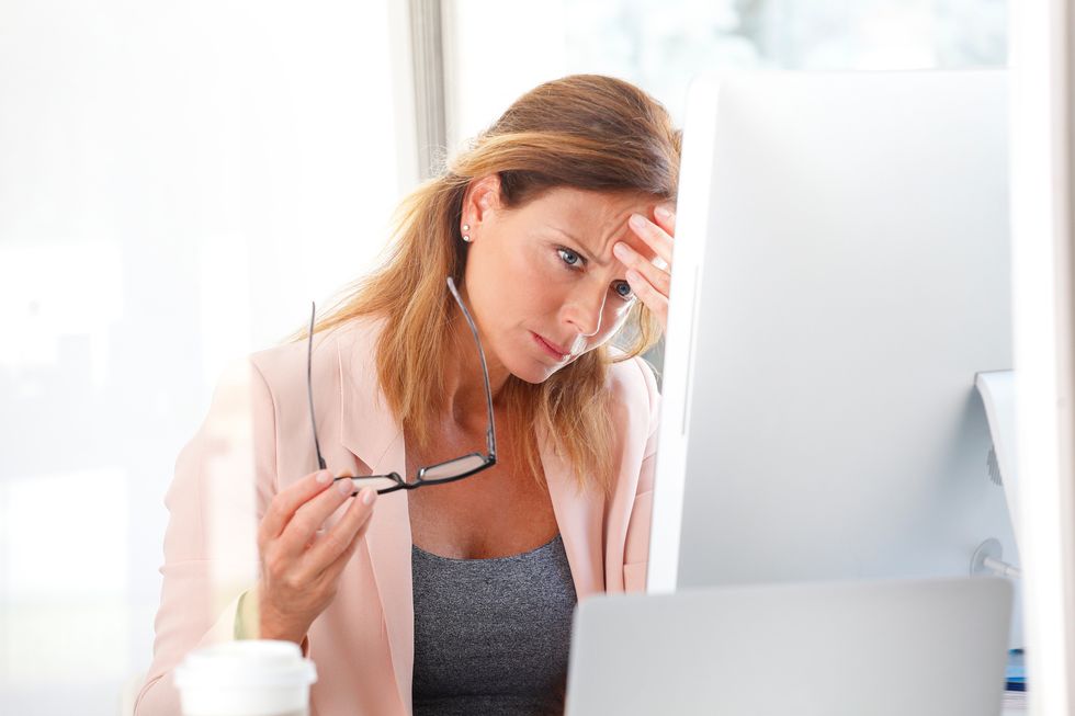 Portrait of an exhausted businesswoman sitting at her desk in an office an working on computer.