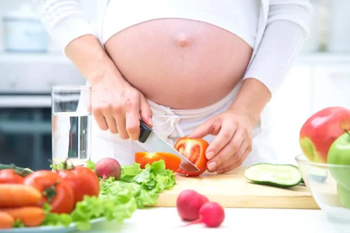 pregnant woman chopping vegetables