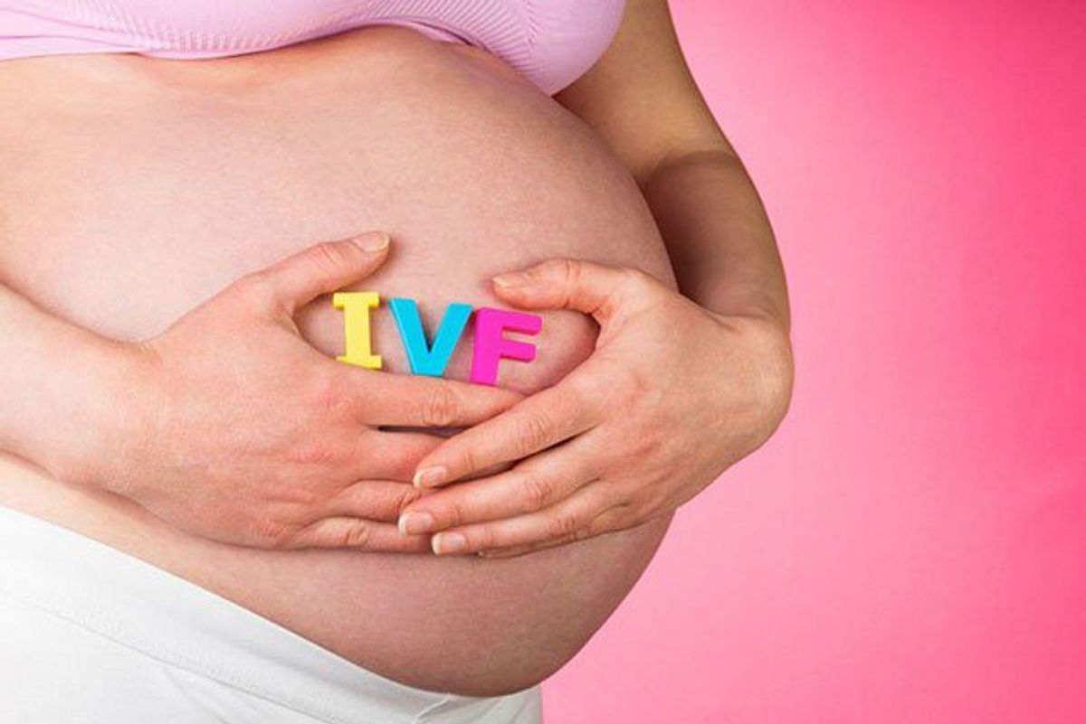 pregnant woman holding the letters IVF at her stomach