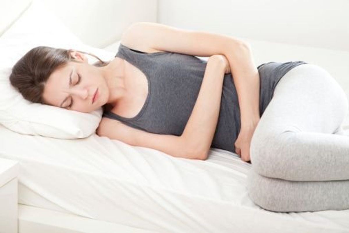 pregnant woman laying in bed with the stomach flu